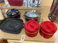 Full lot showing roaster, soup pot, steamer set, two red insulated hot pots