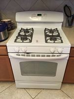 Front view of white GE gas range showing oven door, storage drawer, control knobs and burners