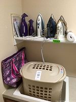 Shelf with 3 irons, 2 purple Joy Mangano steamers, roll of shelf liner, papers