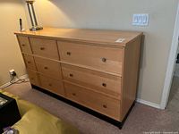 Front view of light wood nine-drawer dresser with knobs visible
