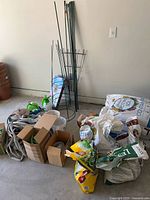 Overall view of lot showing soil bags, hoses, stakes, sprayer and tomato cage