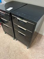 Two black metal 3-drawer cabinets on casters side by side