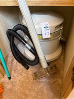 Canister unit with hose, wand and floor head inside cabinet