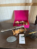 Group shot showing large cannon, small cannon, belt buckle, miniature tanks in pink case