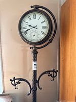 Full view of floor clock showing dial, thermometer, hanger hooks and stand