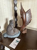 Ironwood marlin carving and ceramic otter figurine side by side
