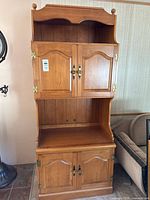 Full view of wooden hutch showing upper open shelf, upper doors, center display area, lower doors