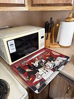 Microwave, paper towel holder, knife block, serving tray shown together on countertop