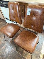 Two brown vinyl chairs with metal frames side by side