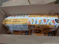Open shipping case showing four sealed packs of Hello Bello diapers