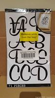 Front of sealed Sticko sticker pack, black script letter sheet visible