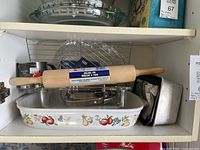 Shelf with Pyrex glass dish, ceramic fruit-motif baker, rolling pin, sifters, loaf pans, cooling racks
