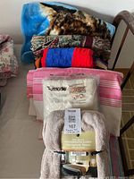 Stack of fleece blankets and packaged throws on bed