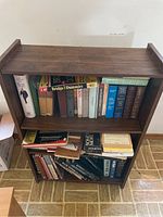 Dark wood two-shelf bookcase filled with books