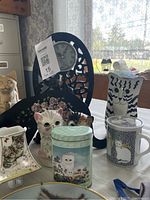 Close-up of clock, mugs, tin and figurines