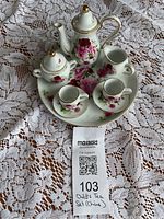 Full child’s china tea set arranged on lace cloth showing all eight pieces