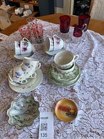 Overall lot showing china, red and clear glassware on lace tablecloth