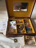 Overview of open jewelry box, contents visible, pendant necklace and instrument pins box in foreground