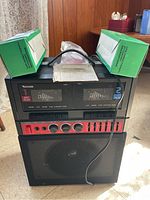 Front view of Venturer dual cassette karaoke machine with built-in speaker, cassette tape and two boxed microphones on top