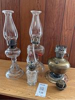 Front view of four oil lamps displayed on wooden surface