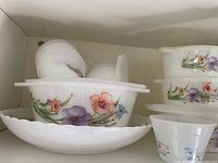 Opal glass casseroles, scalloped bowl, small bowls with lids on left side of cabinet