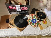 Open cardboard box with stack of paper-sleeved records, loose records spread out in front