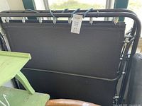 Folded rollaway cot base standing upright showing frame and fabric deck