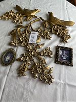 Full lot showing three gold wall plaques and two framed prints