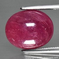 Front view of oval pinkish red ruby cabochon held by tweezers
