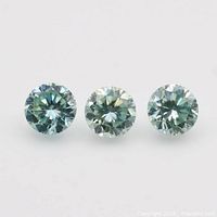 Three round brilliant moissanite stones on white background