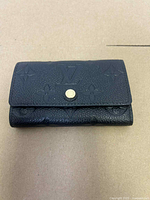 Front view of black Louis Vuitton key holder showing embossing and snap