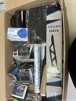 Top view of box showing mug, saw blade pack, adhesive tape, speaker box, various rolls and small items