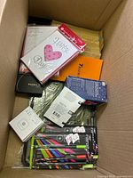 Overview of box showing greeting cards, pen set, retail boxes, wallet, smart device box, baking tray