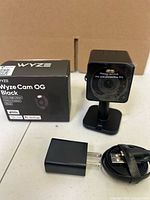 Camera on stand, box, power adapter and cable displayed