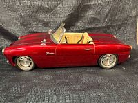 Driver side view of red Bratz convertible car showing wheels, door, interior seats