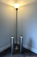 Full view of illuminated brushed nickel torchiere lamp in corner