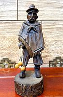 Front view of carved wooden gaucho holding bolos on tree-slice base