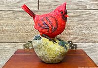 Left side view of red cardinal figurine on rock base
