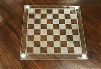 Top view of clear glass chessboard showing alternating frosted squares and corner pads