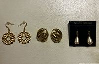 Three pairs of gold tone earrings displayed together