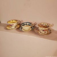 Three teacup and saucer sets displayed side by side