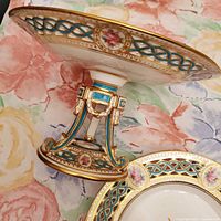 Pedestal cake stand side view with matching plate part visible, shows ornate decoration