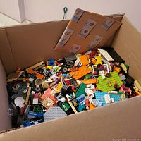 Overview of cardboard box half-filled with loose LEGO pieces