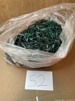 Bag filled with green-wire mini Christmas lights placed on cardboard with lot number card
