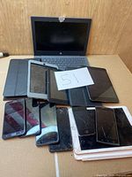 Entire lot showing HP laptop, stack of tablets and phones