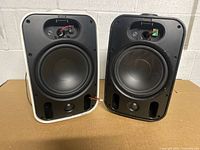 Front view of both speakers without grilles showing woofers and ports