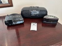 Front view showing Sony clock radio, Panasonic clock radio with speakers, Advance alarm clock