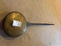 Top view of brass bed warmer showing pierced decorative lid and attached iron handle