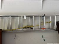 Full view of Louisville aluminum extension ladder hung on wall showing rope and hanger