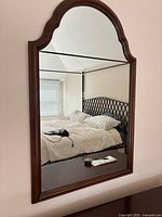 Front view of arched wood-framed wall mirror on wall